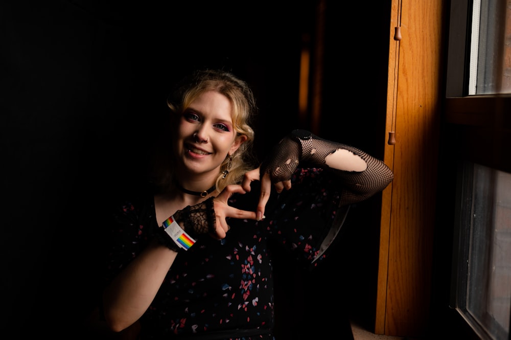 a woman in a black dress pointing at the camera