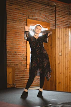 A confident speaker standing tall on stage with arms wide open, embodying fearless energy.