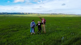 A happy family standing on their newly purchased parcel of land with mountains in the background.