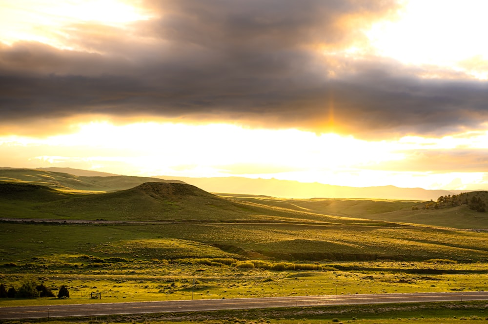 the sun shines through the clouds over the rolling hills