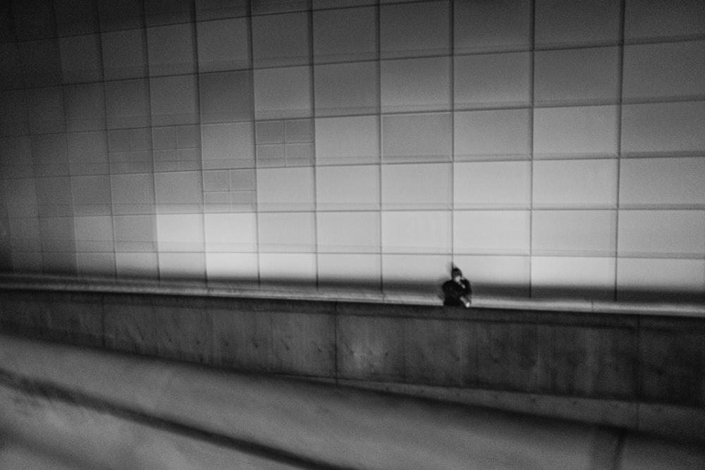 a black and white photo of a person sitting on a ledge