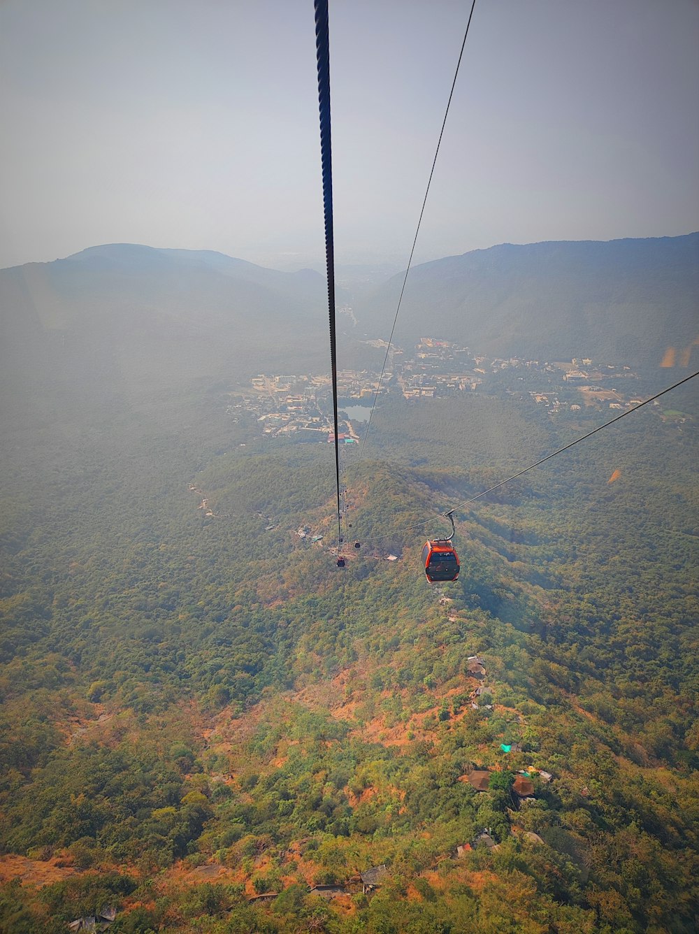 a cable car going over a lush green valley