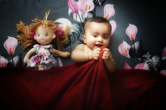 a baby laying on a bed next to two dolls