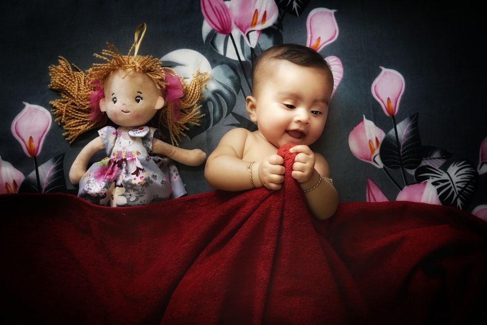 a baby laying on a bed next to a stuffed animal