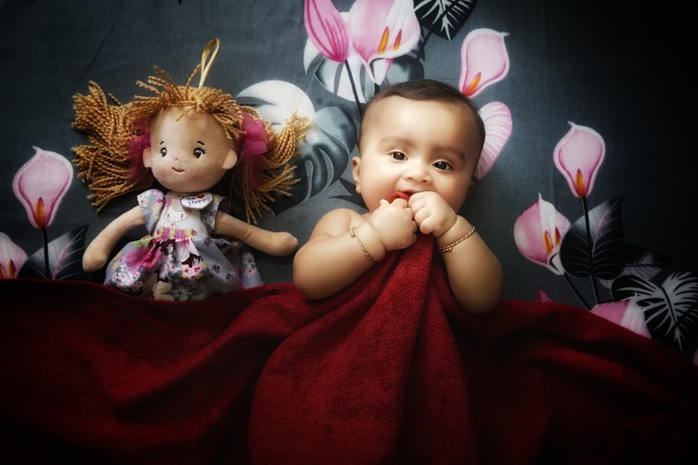 a baby laying on a bed next to a doll