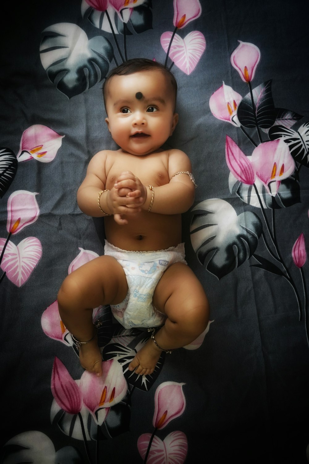 a baby in a diaper sitting on a bed