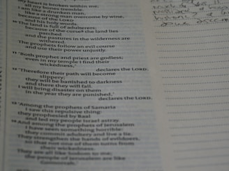 An open book with text on the left page, which appears to be a religious scripture, possibly from the Bible. The right page is lined, intended for taking notes, with some handwritten notes visible in cursive.