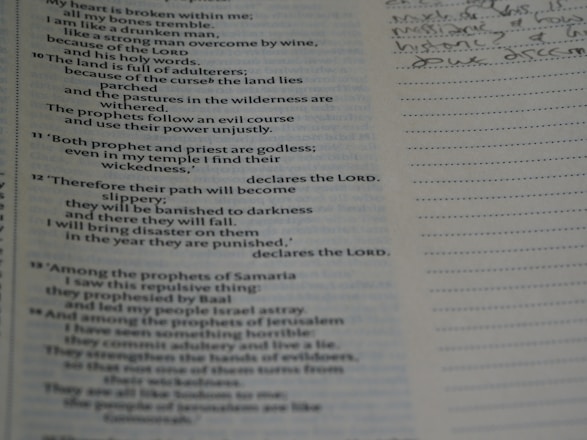 An open book with text on the left page, which appears to be a religious scripture, possibly from the Bible. The right page is lined, intended for taking notes, with some handwritten notes visible in cursive.