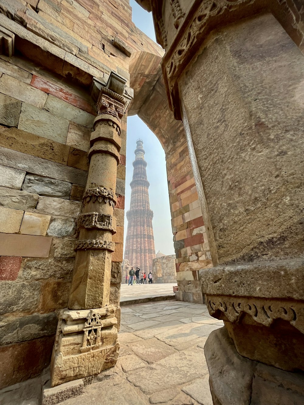 a tall tower towering over a city next to a stone wall