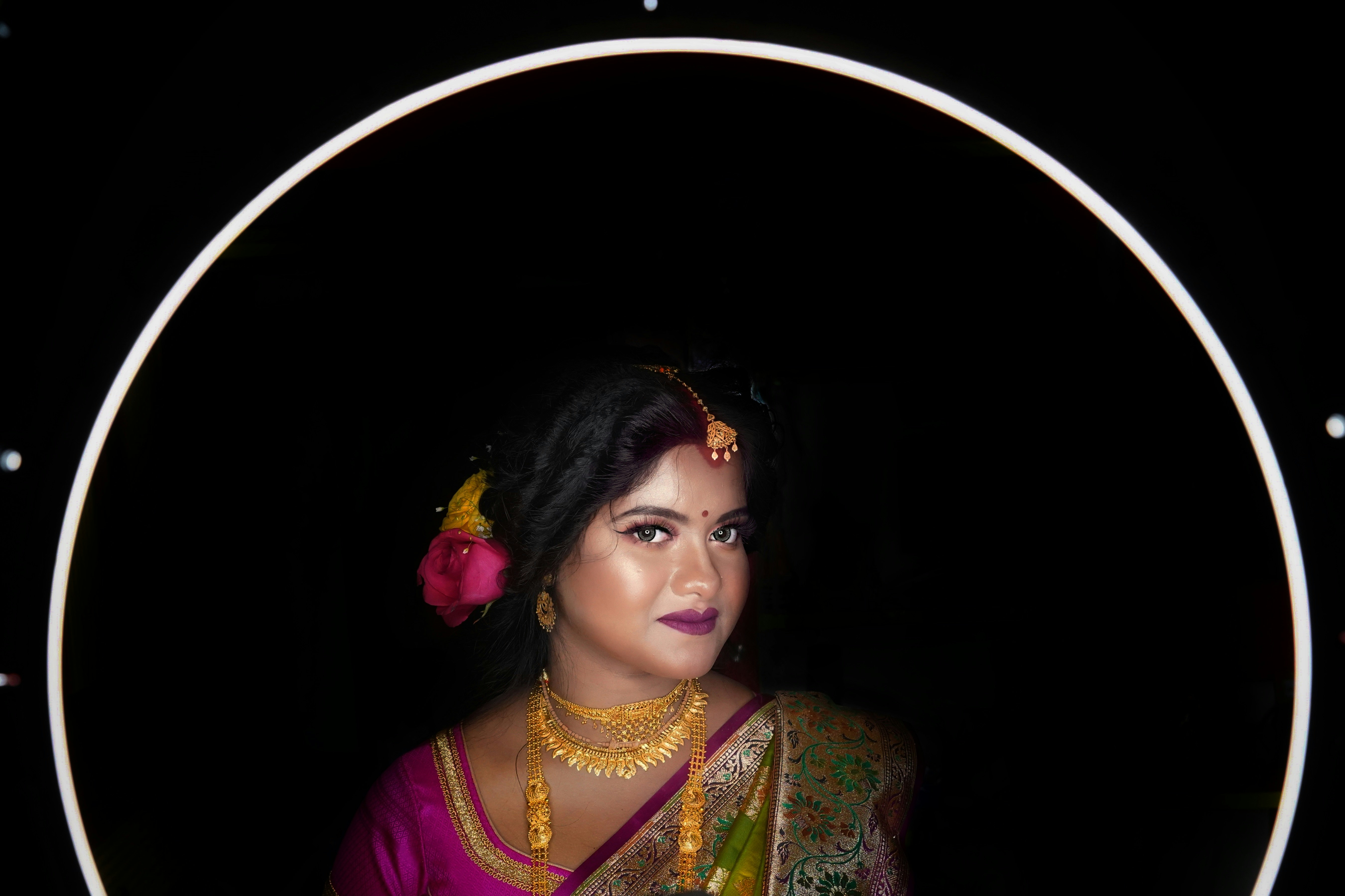 a woman in a pink sari with a flower in her hair
