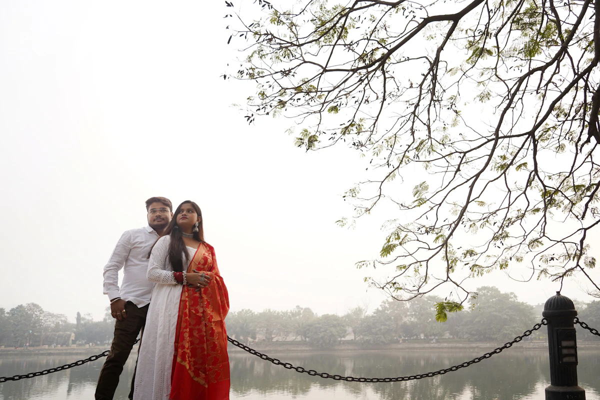 A couple standing side by side near a lake