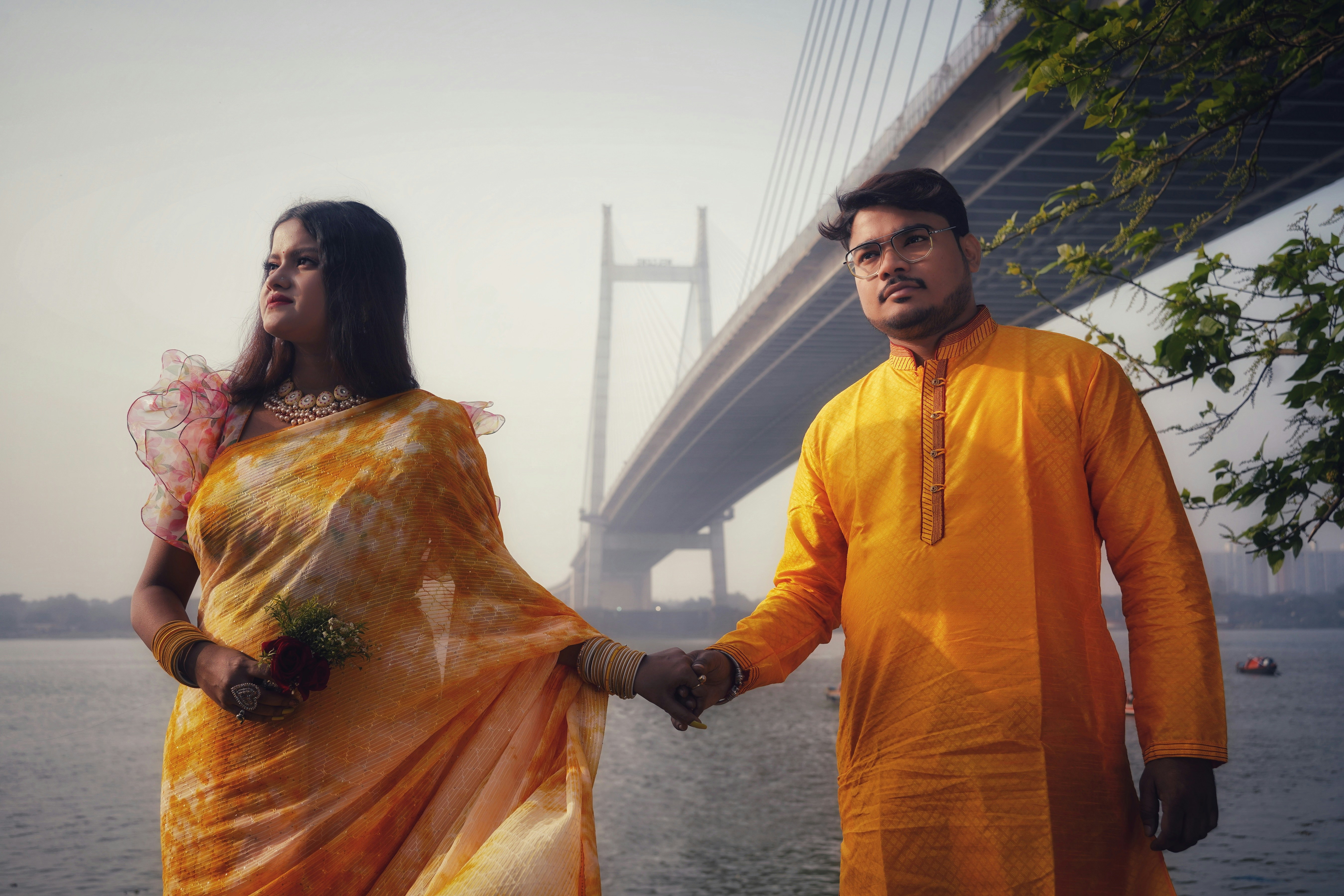 man and woman holding hands in front of bridge