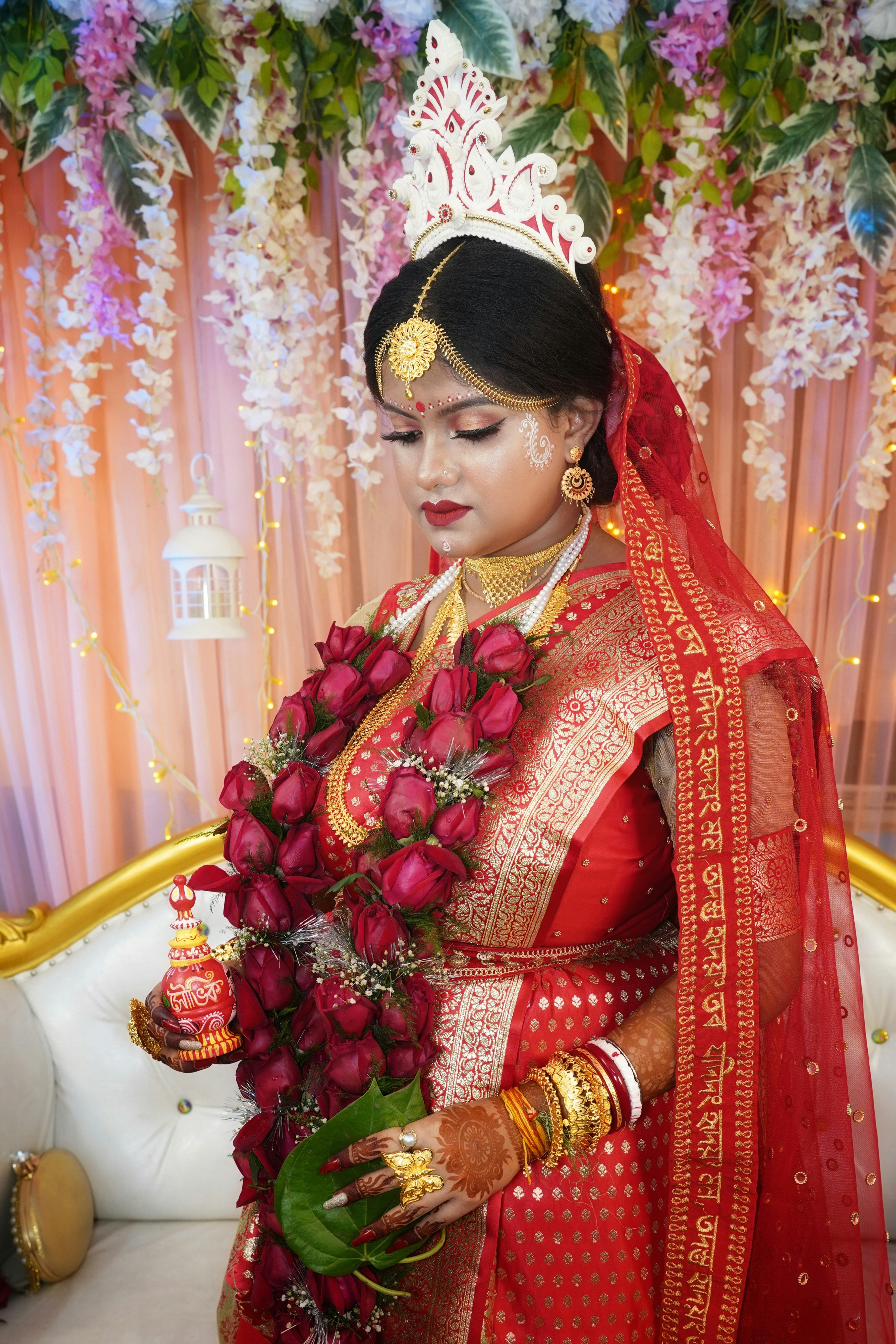 a woman in a red and gold outfit holding a bouquet of flowers