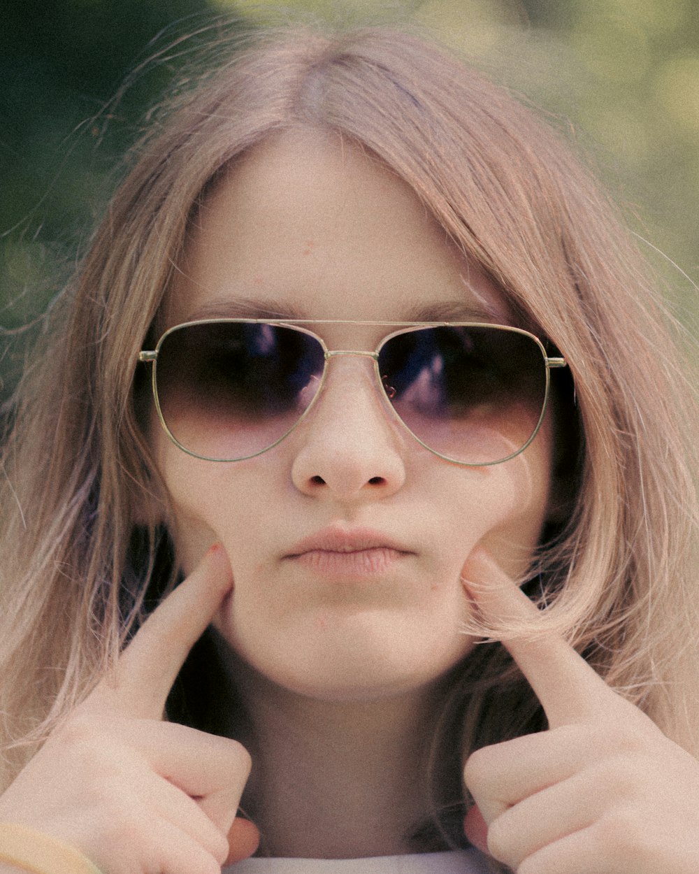 a woman wearing sunglasses and pointing to the side