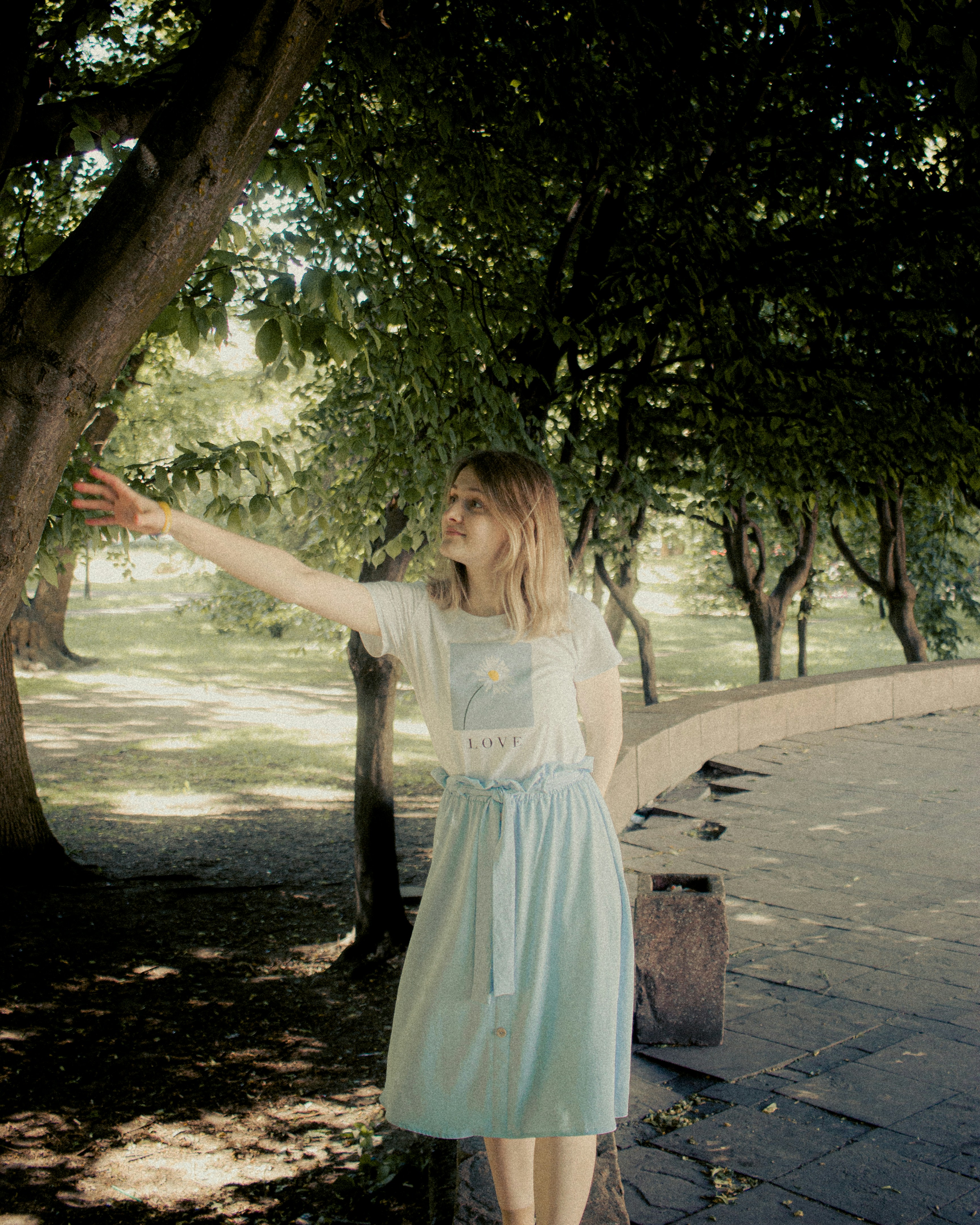 A woman in a blue dress reaching out to a tree photo – Free Portrait ...