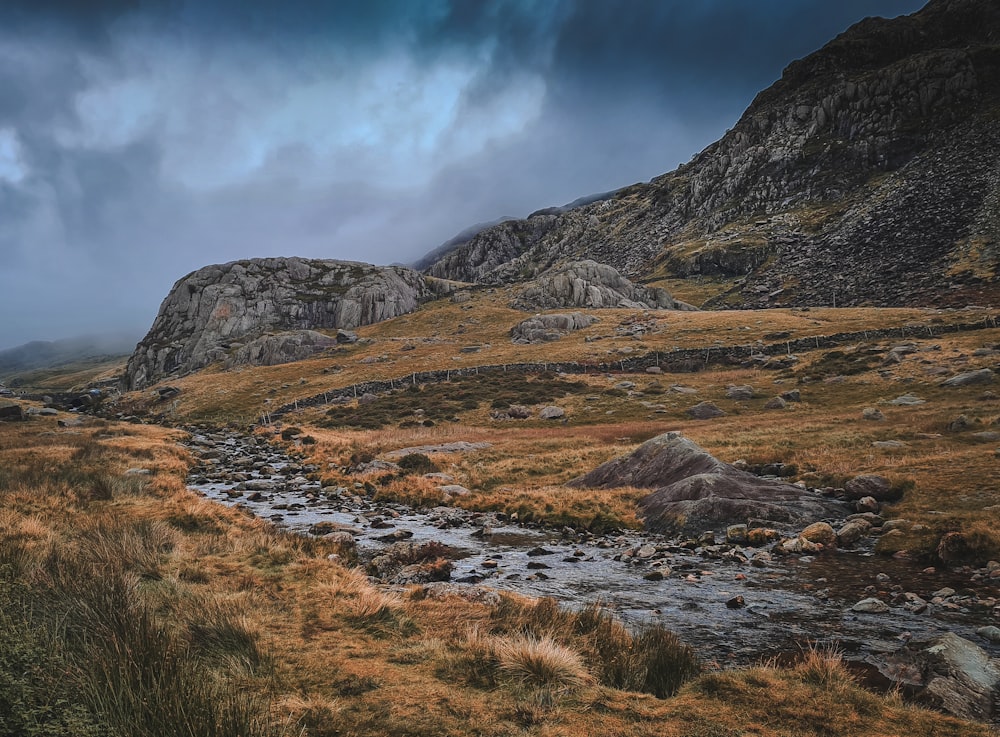 a stream running through a grass covered valley