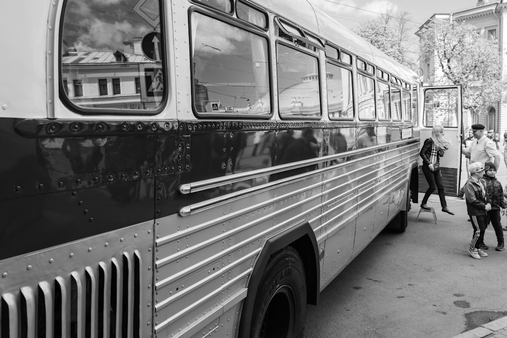a black and white photo of people boarding a bus