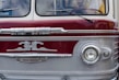 A vintage bus with a distinctive front design, featuring an emblem and retro headlights. The bus has a two-toned color scheme with maroon and silver hues and chrome accents. Visible portions of the interior show the steering wheel and a partial view of a person inside.