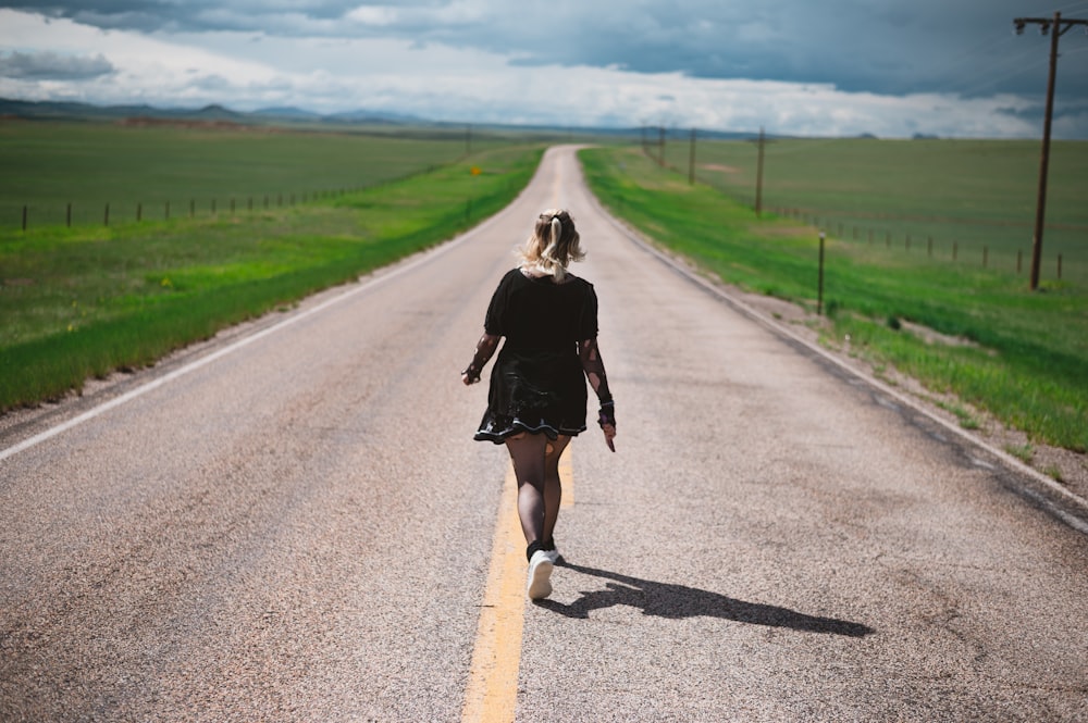 a woman walking down the middle of a road