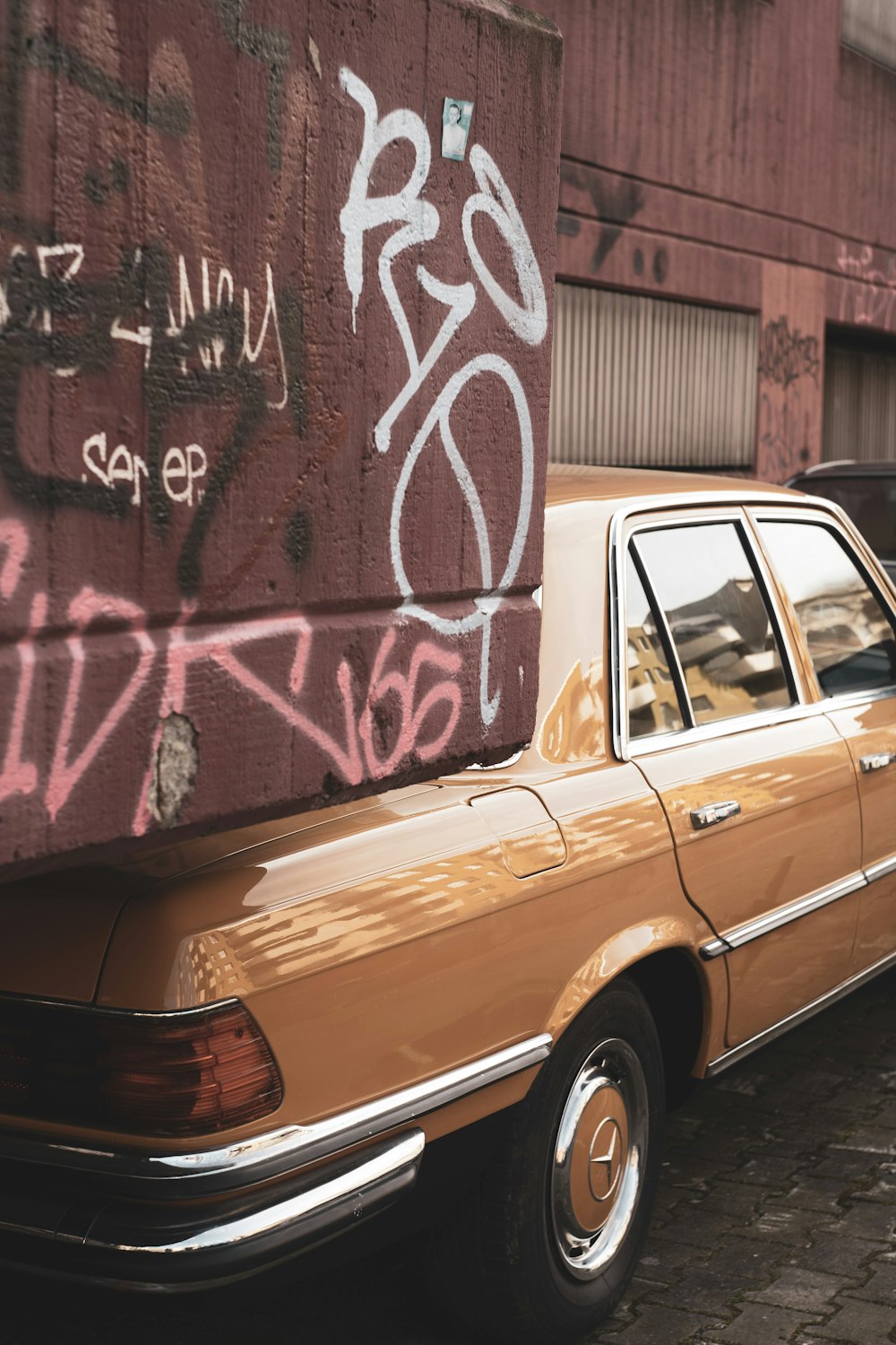 a car parked next to a wall with graffiti on it