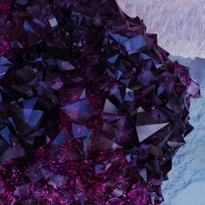 A cluster of deep purple and blue crystals with sharp, angular facets. The background features a subtle texture that resembles rough ice. The light catches on the crystal surfaces, creating a vibrant interplay of colors.