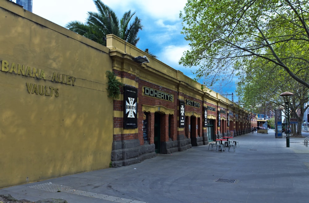 an empty street with tables and chairs in front of a building