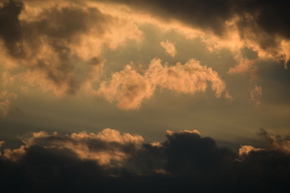 a plane flying through a cloudy sky at sunset