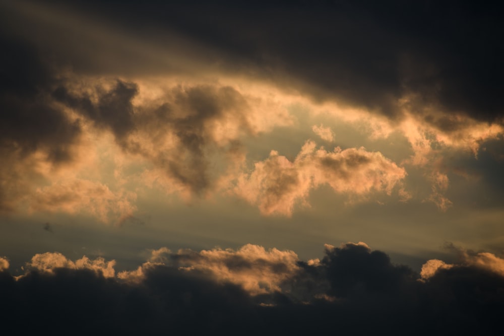 a plane flying through a cloudy sky at sunset