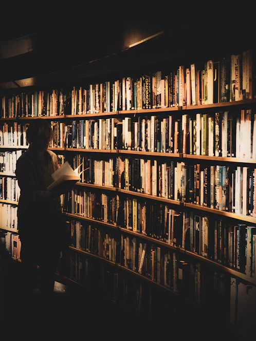 A scholar reviewing a manuscript in a sunlit library filled with classic books
