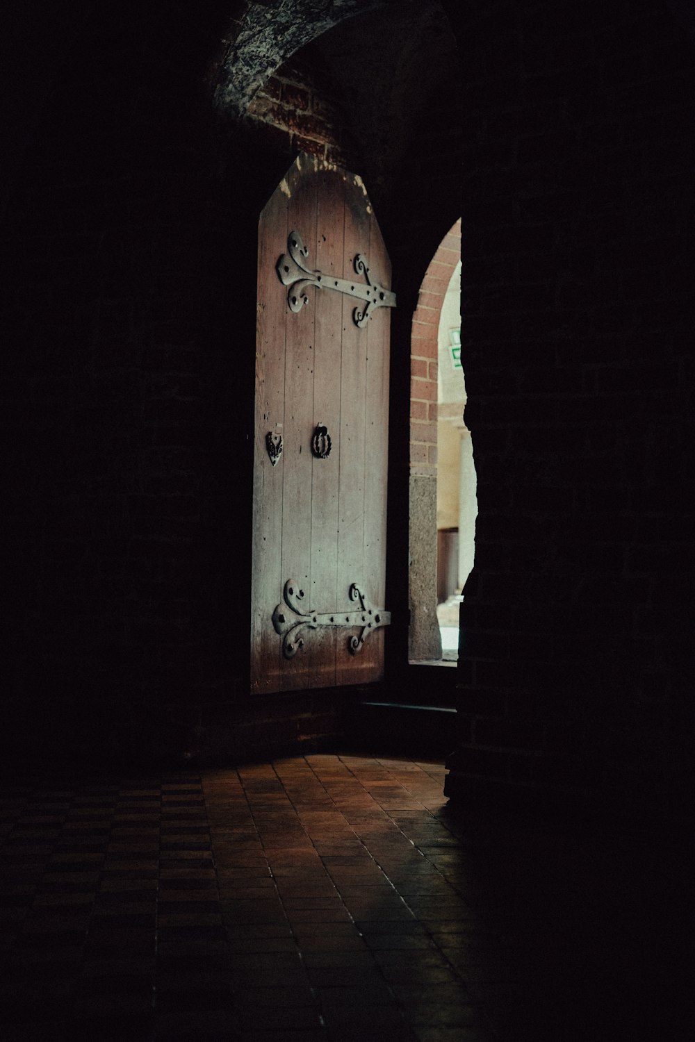 a wooden door in a dark room with a brick floor