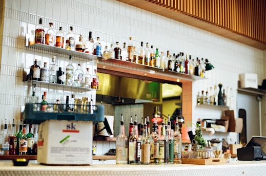 Cozy bar interior with wooden shelves lined with various bottles of liquor and soft warm lighting.