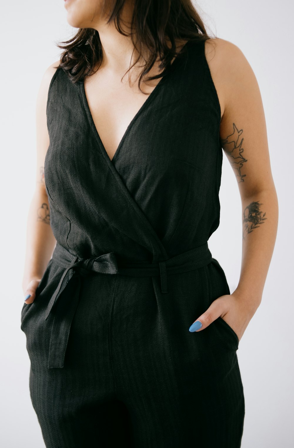 a woman wearing a black jumpsuit with a blue pen in her hand