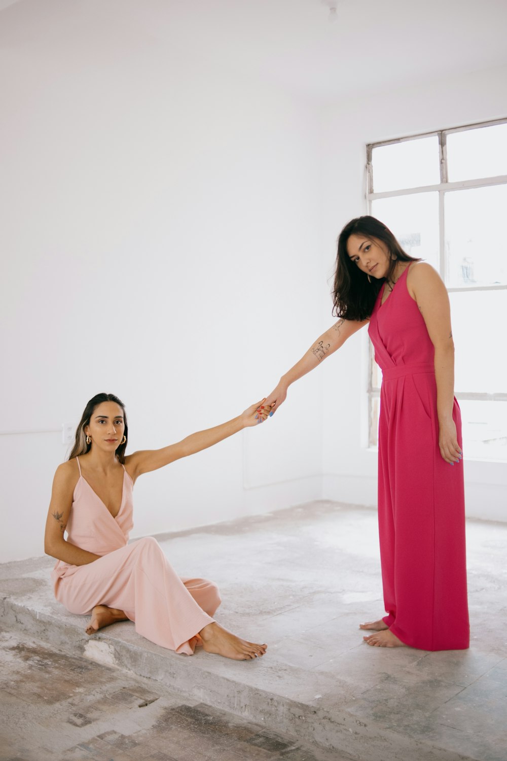 a woman in a pink dress holding the hand of another woman in a pink dress