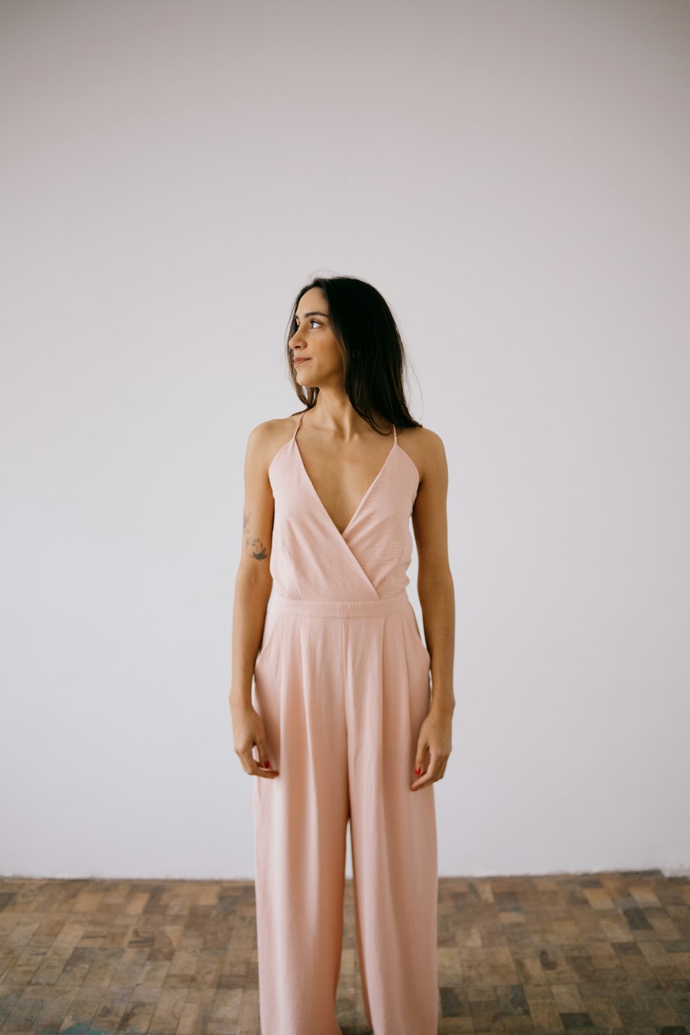 a woman in a pink jumpsuit standing on a wooden floor