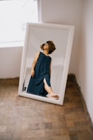 A sleek full-length standing mirror positioned near a bright window with sheer curtains.