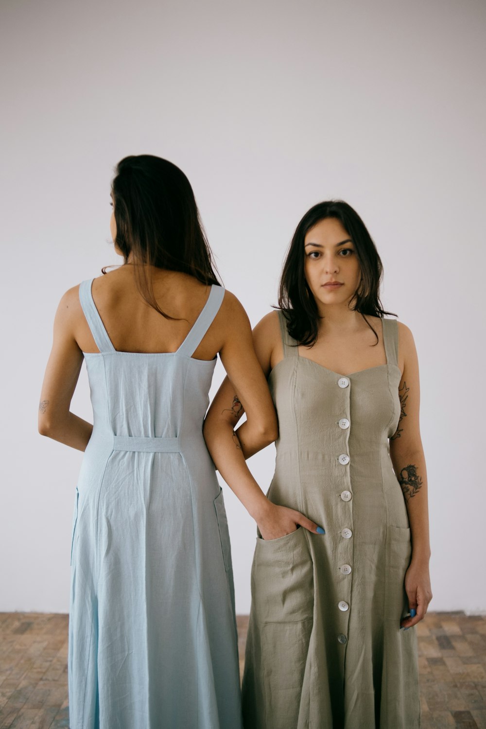 two women standing next to each other in dresses