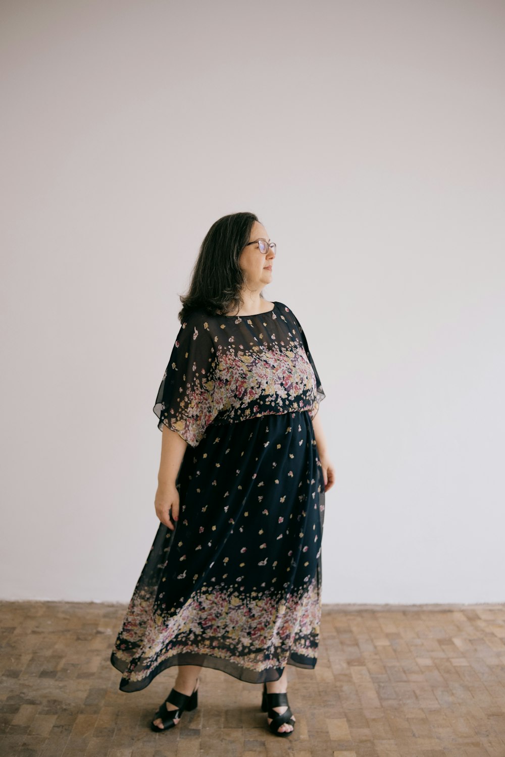 a woman in a dress standing on a wooden floor