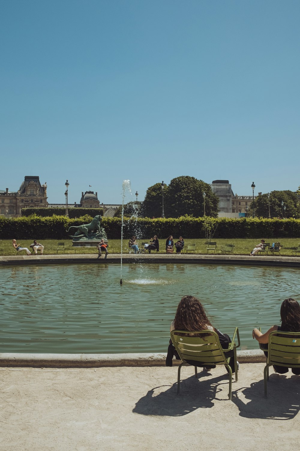 two people sitting on lawn chairs in front of a pond