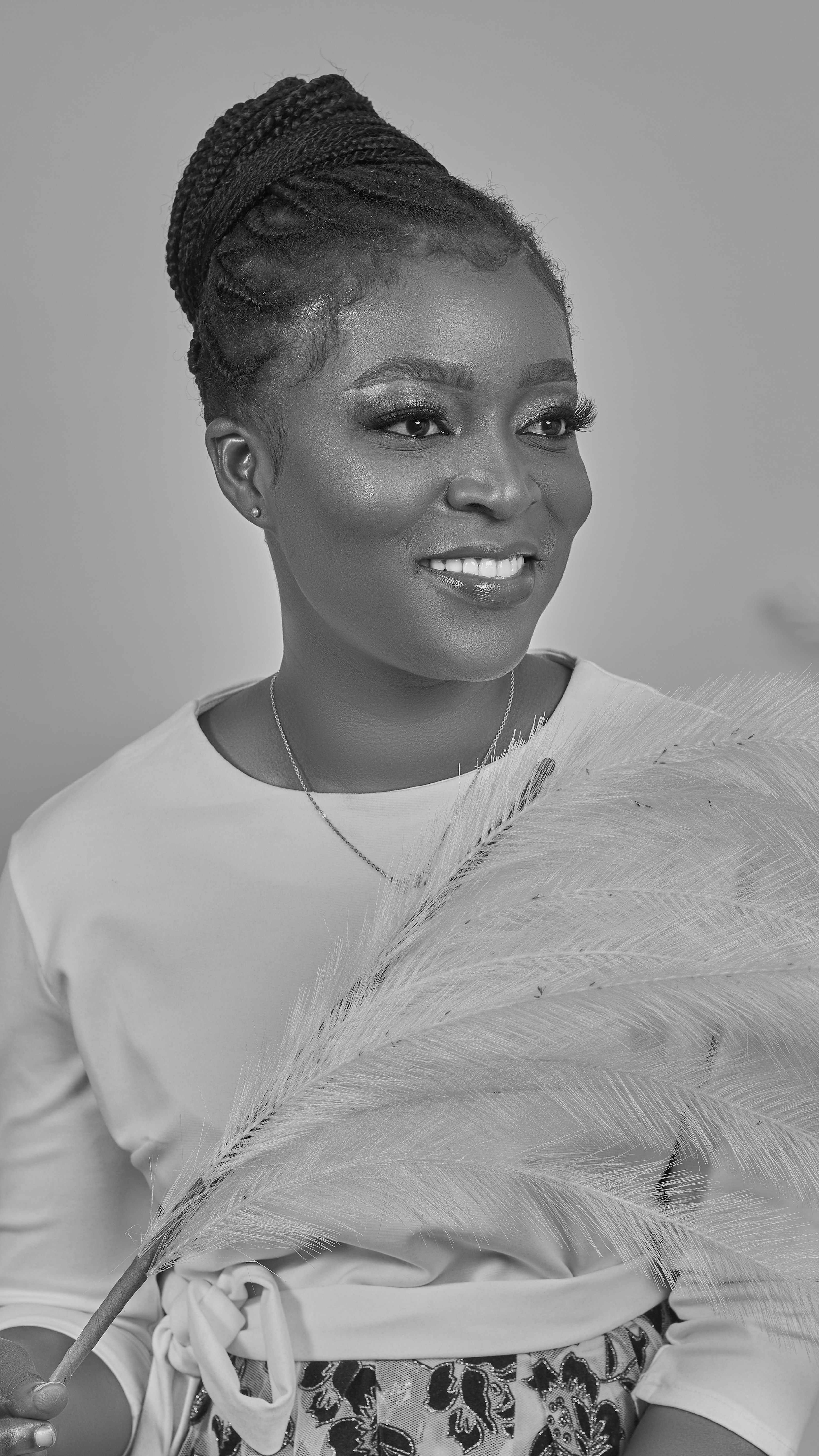 A black woman with braided hair holds a feather.