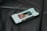 A smartphone lies on a dark leather surface, displaying a contact screen with an image of a person and controls for calling or messaging.