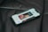 A smartphone lies on a dark leather surface, displaying a contact screen with an image of a person and controls for calling or messaging.