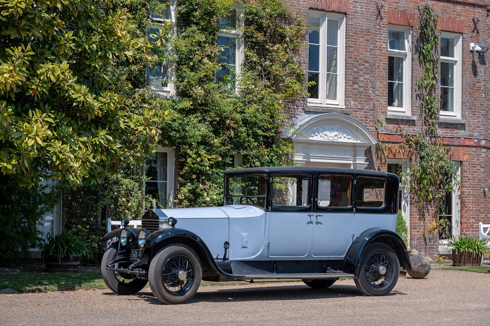 an old blue car parked in front of a brick building