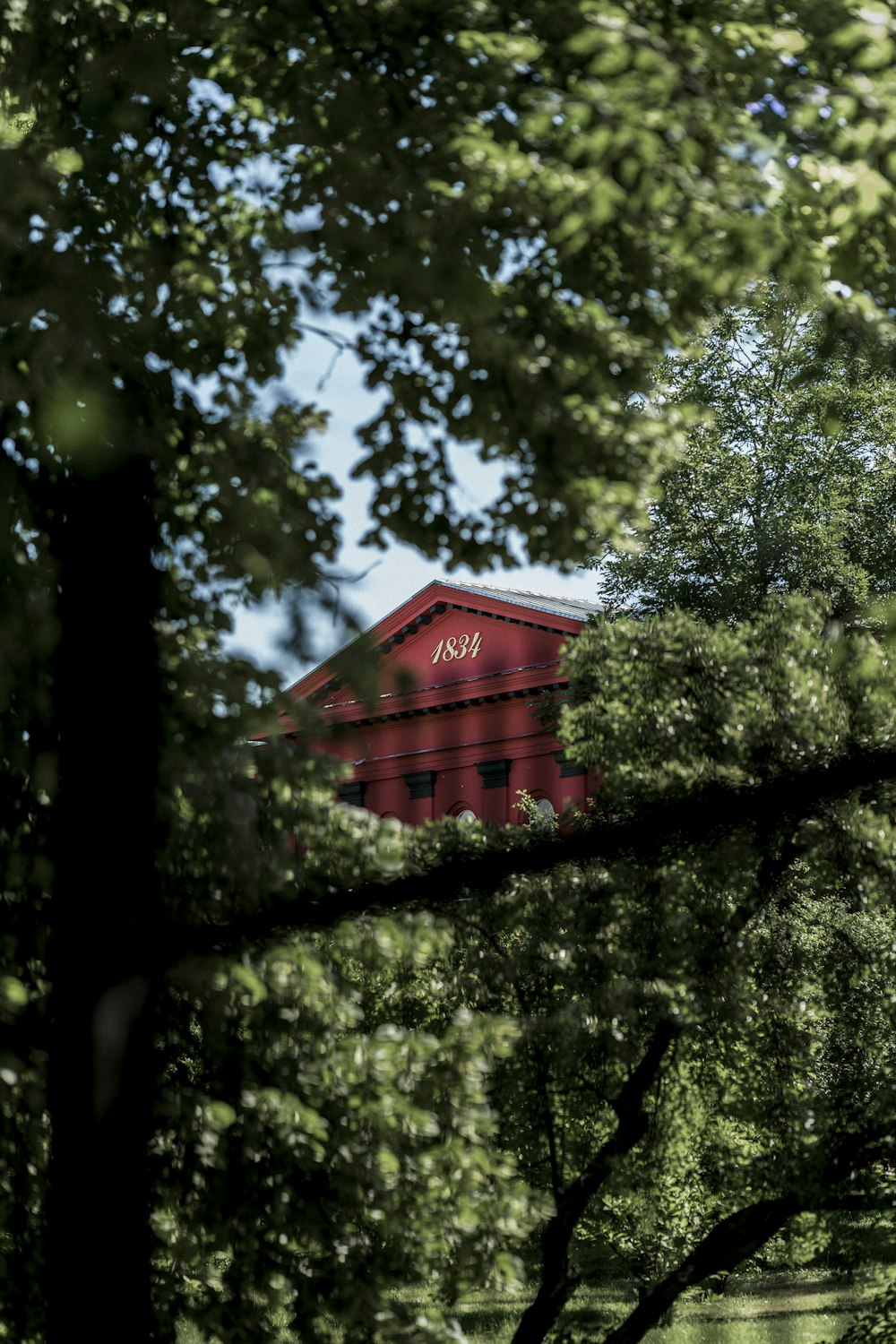 a red building is seen through the trees