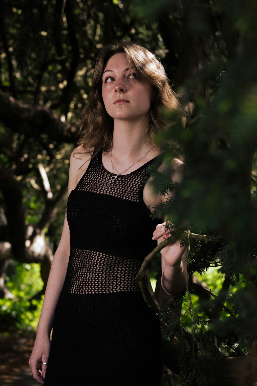 a woman in a black dress standing in a forest