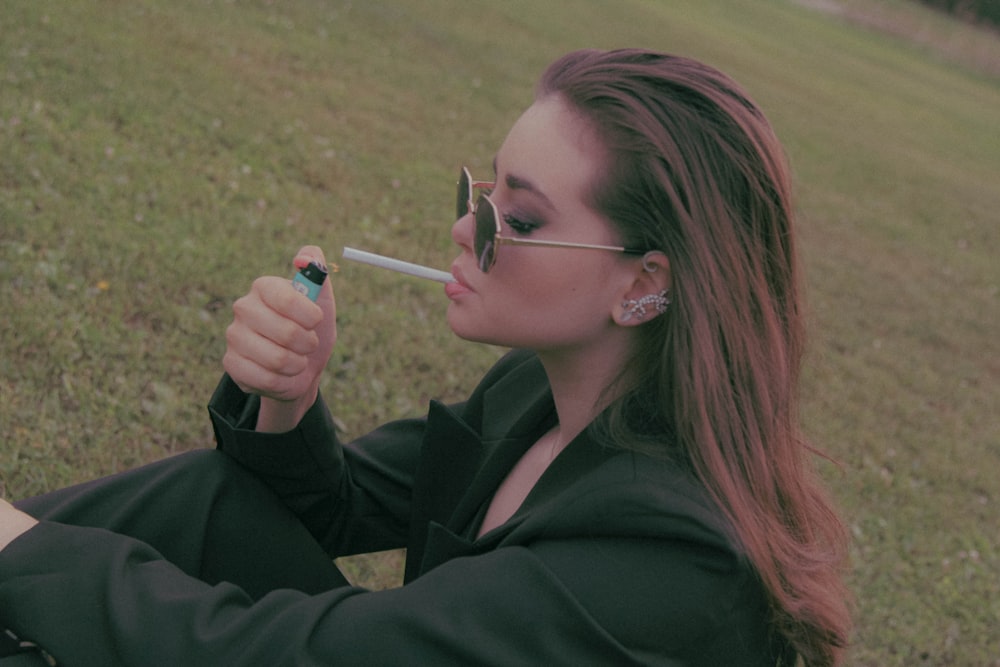 a woman sitting on the ground smoking a cigarette