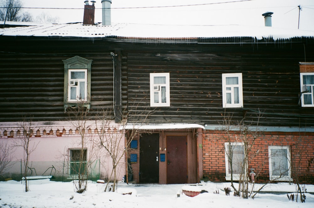 an old wooden house with snow on the ground