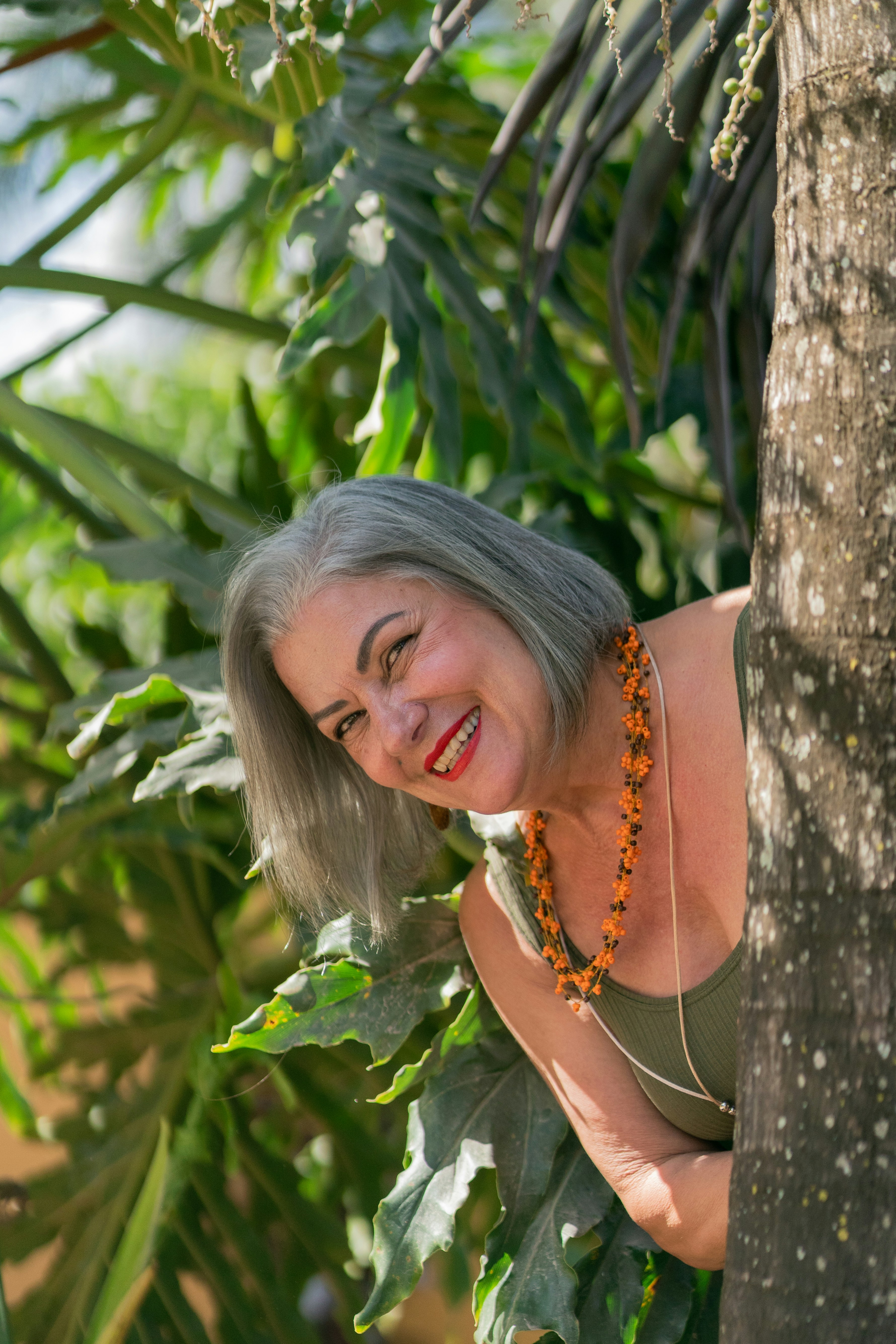 a woman leaning against a tree with a smile on her face