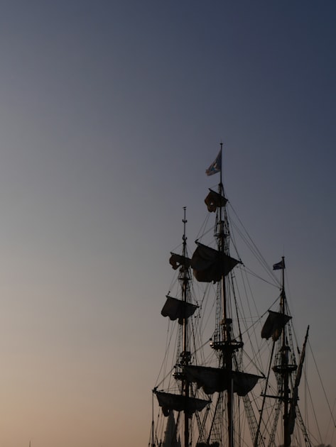 A pirate ship sailing across the ocean at golden sunset with dramatic clouds
