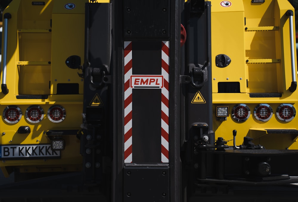 the back of a large yellow truck with a red and white stripe