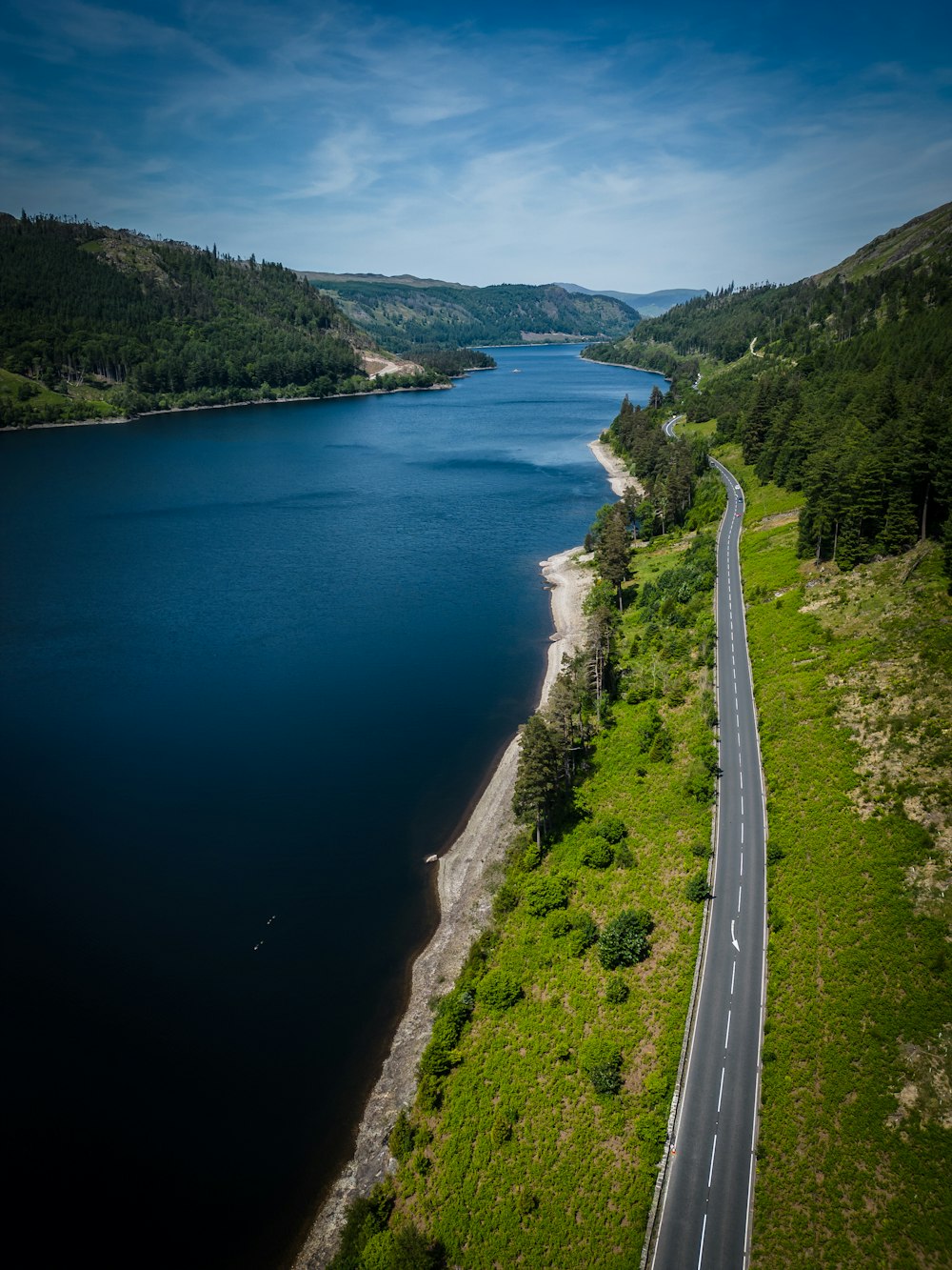 an aerial view of a road next to a body of water